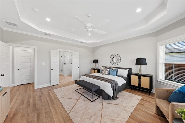 bedroom with ceiling fan, ornamental molding, light hardwood / wood-style flooring, and a tray ceiling