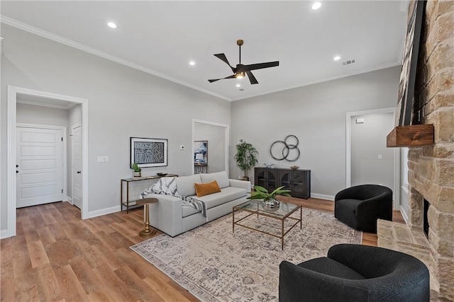 living room with ceiling fan, light hardwood / wood-style floors, crown molding, and a fireplace