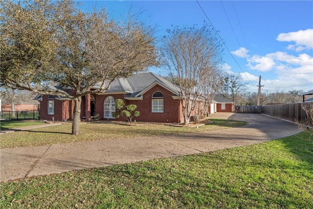 ranch-style home featuring brick siding, driveway, a front yard, and fence