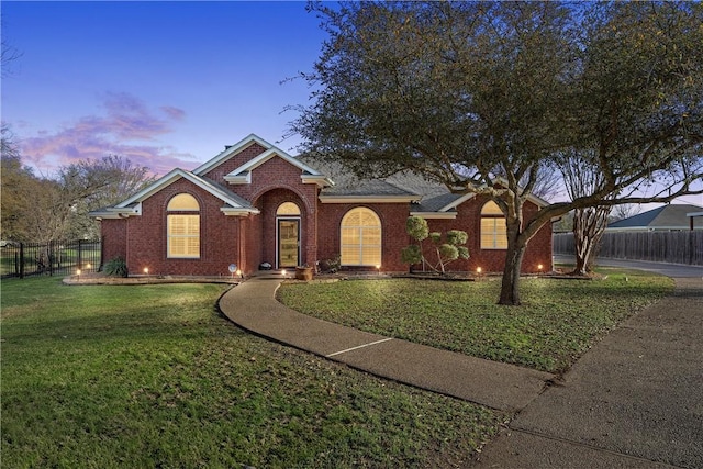 view of front facade featuring a front yard, fence, and brick siding