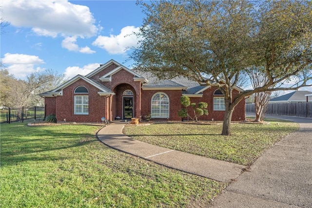 view of front of property with a front lawn, fence, and brick siding