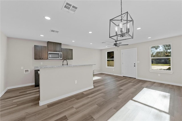 kitchen featuring ceiling fan with notable chandelier, sink, light wood-type flooring, decorative light fixtures, and dark brown cabinetry