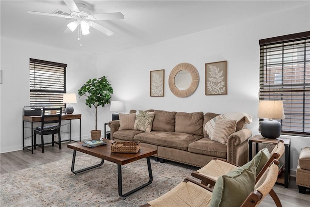 living room featuring visible vents, baseboards, a ceiling fan, and wood finished floors