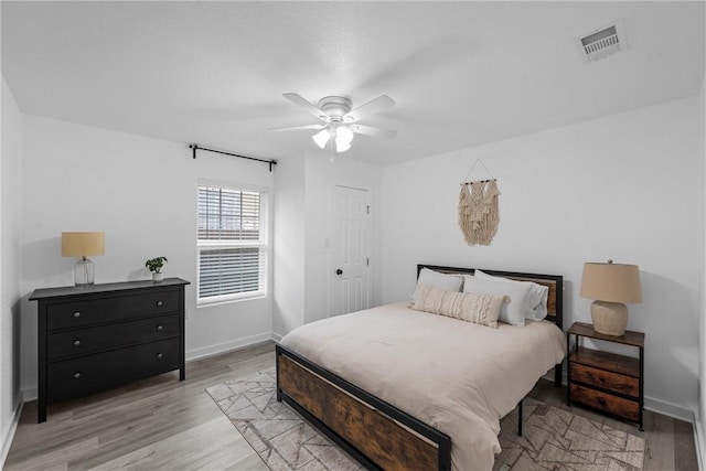 bedroom with visible vents, baseboards, a ceiling fan, and light wood finished floors