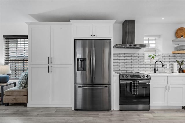 kitchen with a sink, open shelves, white cabinetry, stainless steel appliances, and wall chimney exhaust hood