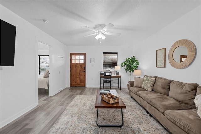 living room with baseboards, ceiling fan, and wood finished floors