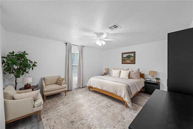 bedroom with light wood-type flooring, visible vents, and a ceiling fan