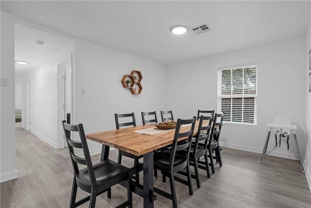 dining room with visible vents, baseboards, and wood finished floors