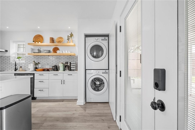 clothes washing area featuring stacked washer / dryer, recessed lighting, and light wood finished floors