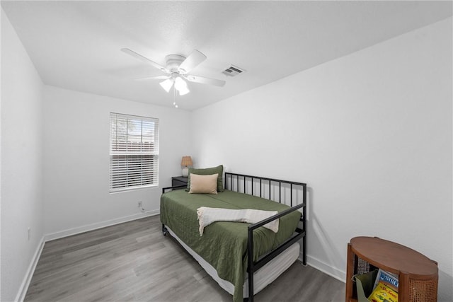 bedroom featuring visible vents, ceiling fan, baseboards, and wood finished floors