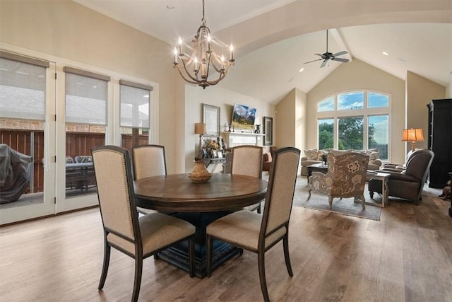 dining space with hardwood / wood-style floors, ceiling fan with notable chandelier, and lofted ceiling