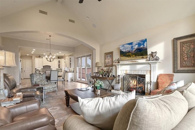 living room with ceiling fan with notable chandelier, wood-type flooring, and high vaulted ceiling