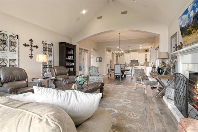 living room featuring hardwood / wood-style flooring, high vaulted ceiling, a tile fireplace, and a chandelier