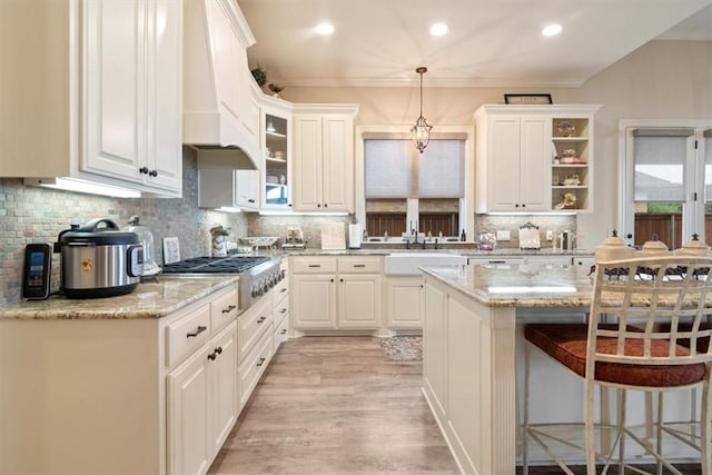 kitchen featuring light stone counters, decorative light fixtures, decorative backsplash, white cabinets, and light wood-type flooring