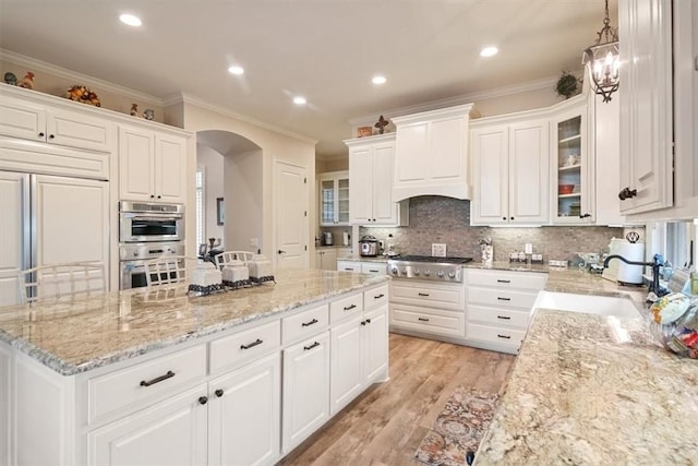 kitchen featuring white cabinetry, sink, hanging light fixtures, and ornamental molding