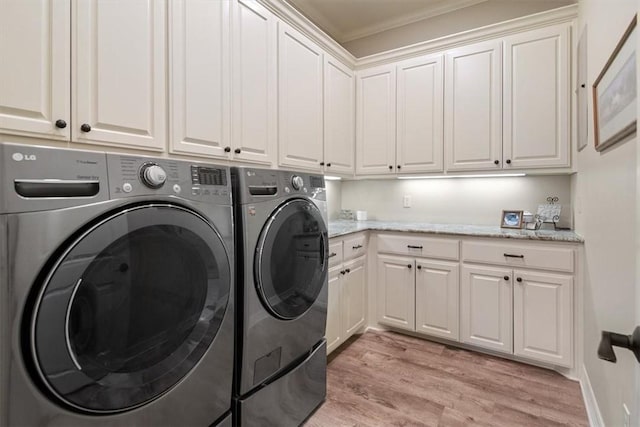 laundry area with crown molding, washer and clothes dryer, cabinets, and light wood-type flooring