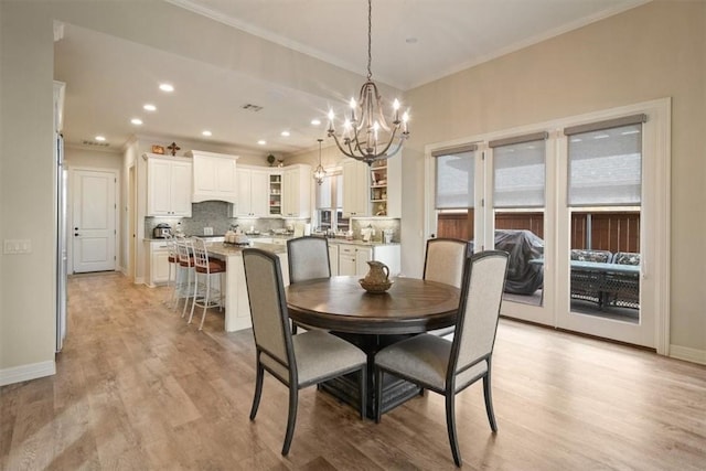 dining room featuring crown molding, light hardwood / wood-style flooring, and a chandelier