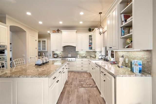 kitchen featuring light stone countertops, light wood-type flooring, decorative light fixtures, and white cabinetry