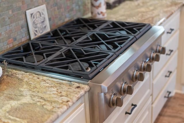 room details featuring white cabinets, stainless steel range oven, and tasteful backsplash