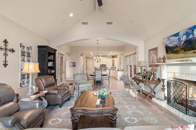 living room featuring ceiling fan with notable chandelier, wood-type flooring, and vaulted ceiling with beams