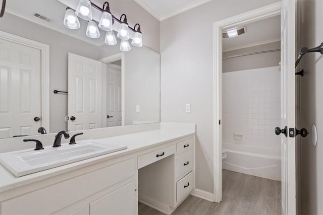 bathroom featuring vanity, wood-type flooring, tiled shower / bath combo, and ornamental molding