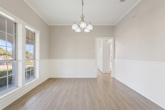 unfurnished room with a notable chandelier, light wood-type flooring, plenty of natural light, and ornamental molding