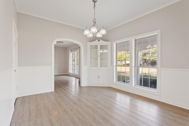 unfurnished dining area with crown molding, light hardwood / wood-style floors, and a notable chandelier