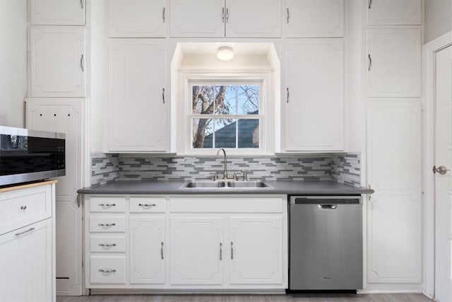 kitchen with tasteful backsplash, sink, white cabinets, and stainless steel appliances