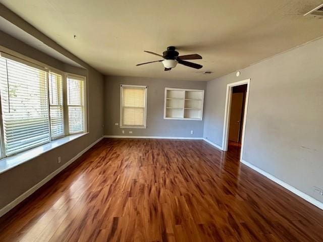 spare room featuring built in features, ceiling fan, and dark wood-type flooring