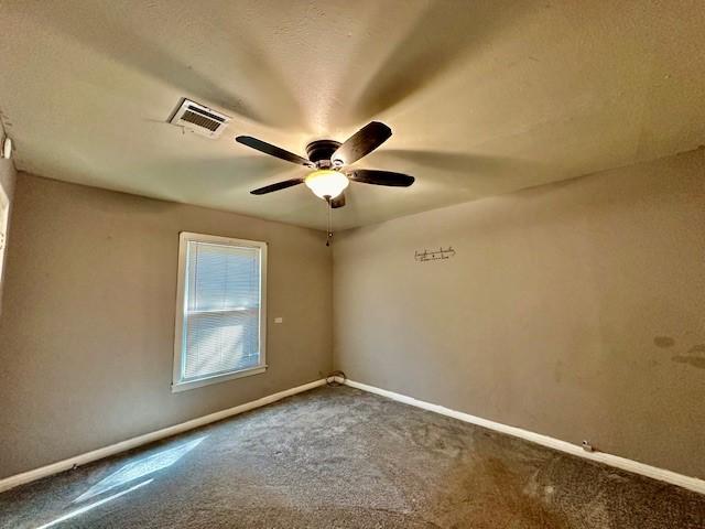 carpeted empty room featuring ceiling fan and a textured ceiling