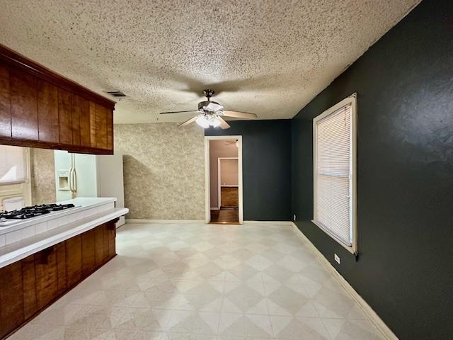 kitchen featuring a textured ceiling, ceiling fan, white refrigerator with ice dispenser, and gas cooktop