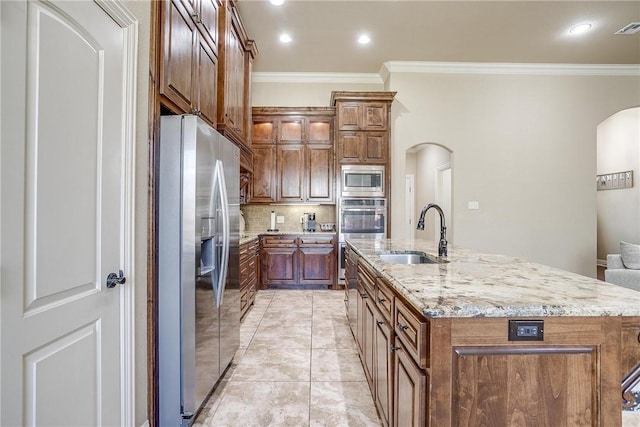 kitchen with a kitchen island with sink, crown molding, sink, appliances with stainless steel finishes, and tasteful backsplash