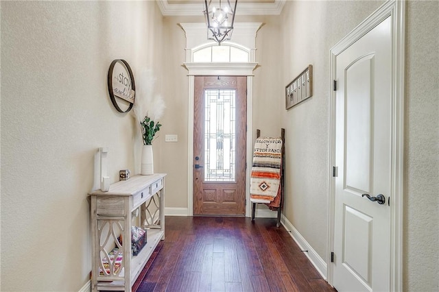 foyer with dark hardwood / wood-style flooring, ornamental molding, and a chandelier