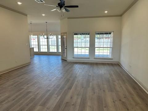 unfurnished room with wood finished floors, plenty of natural light, ceiling fan with notable chandelier, and ornamental molding