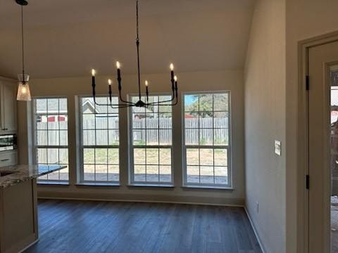 unfurnished dining area with lofted ceiling, dark wood-style floors, baseboards, and a chandelier