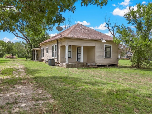 rear view of property featuring central AC unit, covered porch, and a yard