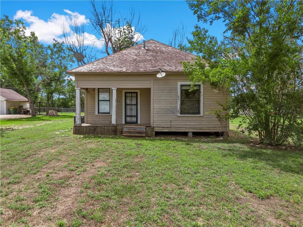 back of property with a lawn and covered porch