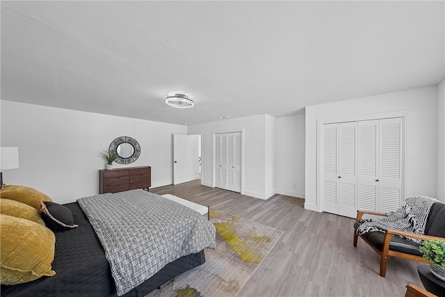 bedroom featuring two closets and light hardwood / wood-style flooring