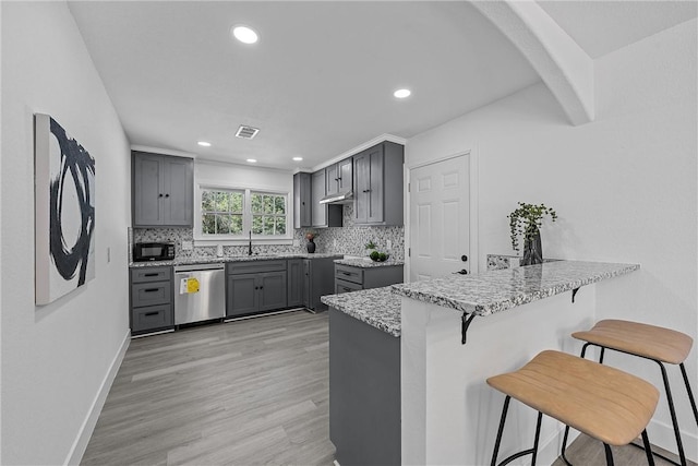 kitchen with a kitchen bar, light wood-type flooring, tasteful backsplash, gray cabinetry, and dishwasher