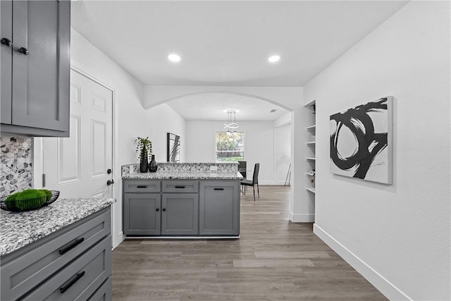 kitchen with light stone countertops, hardwood / wood-style floors, and gray cabinets