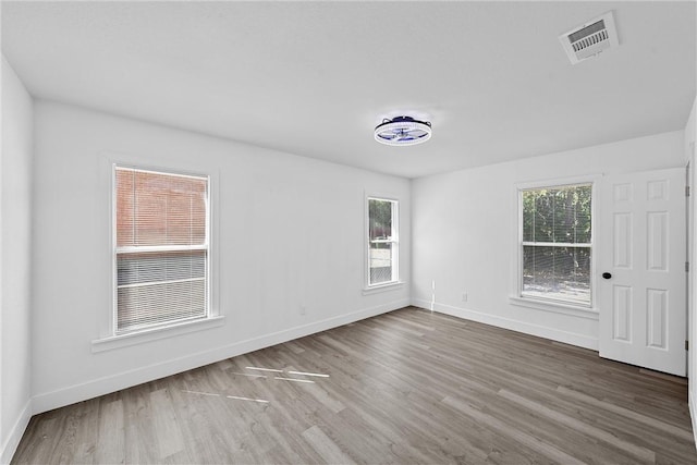 unfurnished room with hardwood / wood-style flooring and a healthy amount of sunlight