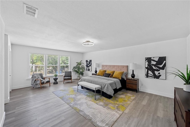 bedroom featuring light hardwood / wood-style floors and a textured ceiling