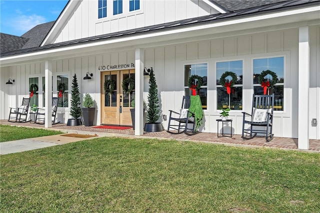 view of exterior entry featuring a porch and a yard