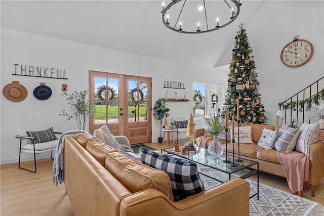 living room with french doors, high vaulted ceiling, light hardwood / wood-style floors, and a notable chandelier