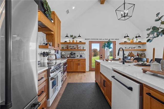 kitchen with pendant lighting, sink, light wood-type flooring, stainless steel appliances, and a chandelier