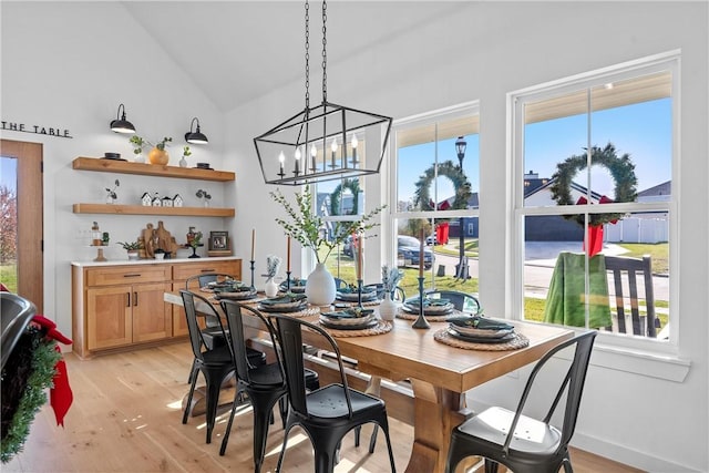 dining space featuring light hardwood / wood-style flooring, a chandelier, and lofted ceiling