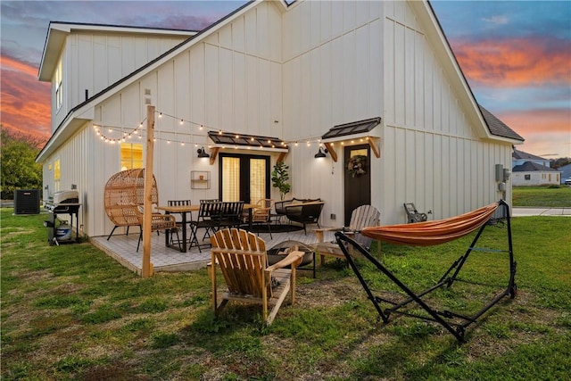 back house at dusk featuring a patio area, a yard, and central AC