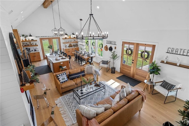 living room with french doors, light wood-type flooring, and high vaulted ceiling