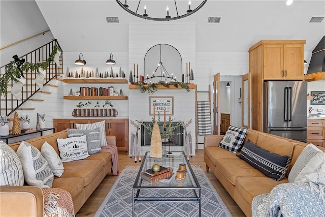 living room featuring wooden walls, light hardwood / wood-style floors, and an inviting chandelier