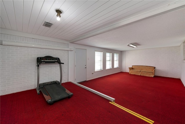 workout area featuring brick wall and dark carpet